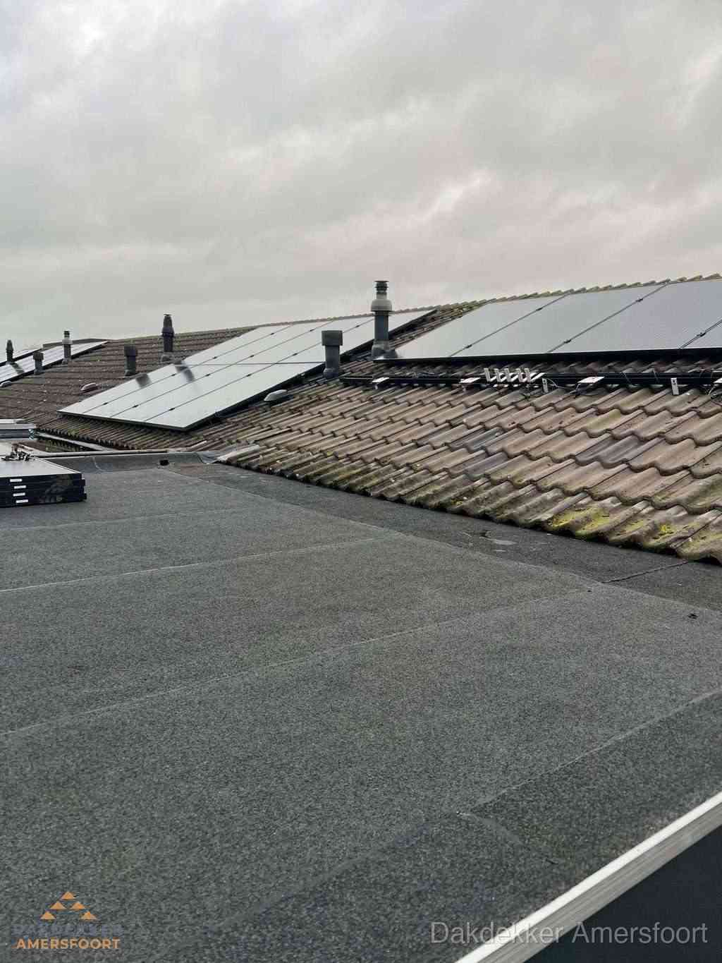 Plat dak inspectie met bitumen bedekking naast schuin pannendak in Amersfoort