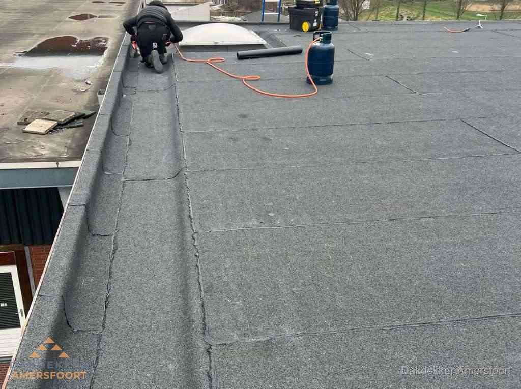 Dakdekker repareert bitumen dakbedekking op groot plat dak in Amersfoort